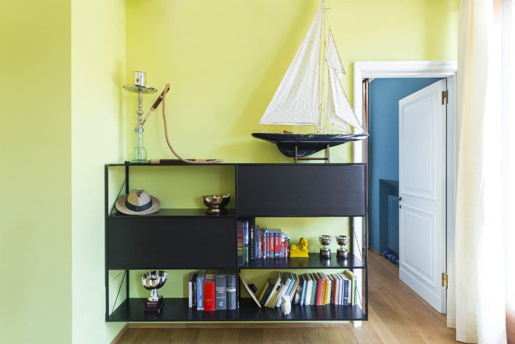 Bright Yellow Wall With Black Bookshelf And Nautical Decor In Modern Apartment.